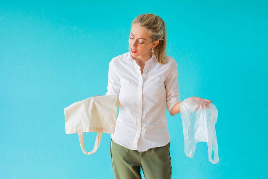 femme qui choisit entre sac plastique et sac en tissu.